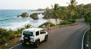 A tourists' rental car parked on a scenic coast road, showcasing the experience of renting a car in Barbados.